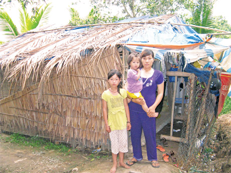 Chị Nga, cháu Ngọc Huy (giữa) và cháu Cẩm Tú bên cạnh căn chòi lá tạm bợ.