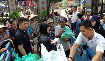 Thầy Minh Huy (người mặc áo thun đen) đang phát quà Tết tại chùa Phổ Đức.