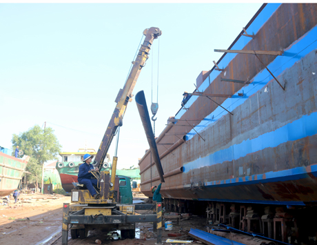 Các thanh thép nặng được công nhân dùng cần cẩu để chuyển lên cao.