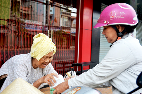 Cụ bà trao gói xôi cho thực khách thật dung dị, thân thiện. 