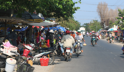 Các tiểu thương bày bán các mặt hàng và để dù bạt, mái che ra sát mép lộ nhựa.