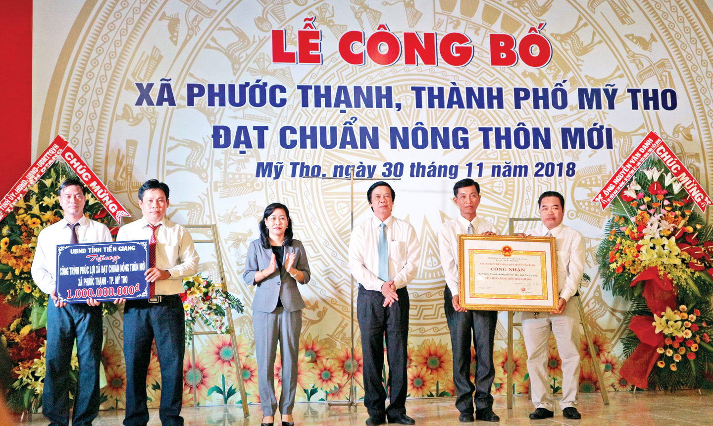 Đồng chí Nguyễn Văn Danh và đồng chí Châu Thị Mỹ Phương trao Bằng công nhận xã đạt chuẩn NTM và Bảng tượng trưng công trình phúc lợi trị giá 1 tỷ đồng cho xã Phước Thạnh.    	      Ảnh:  LÝ OANH