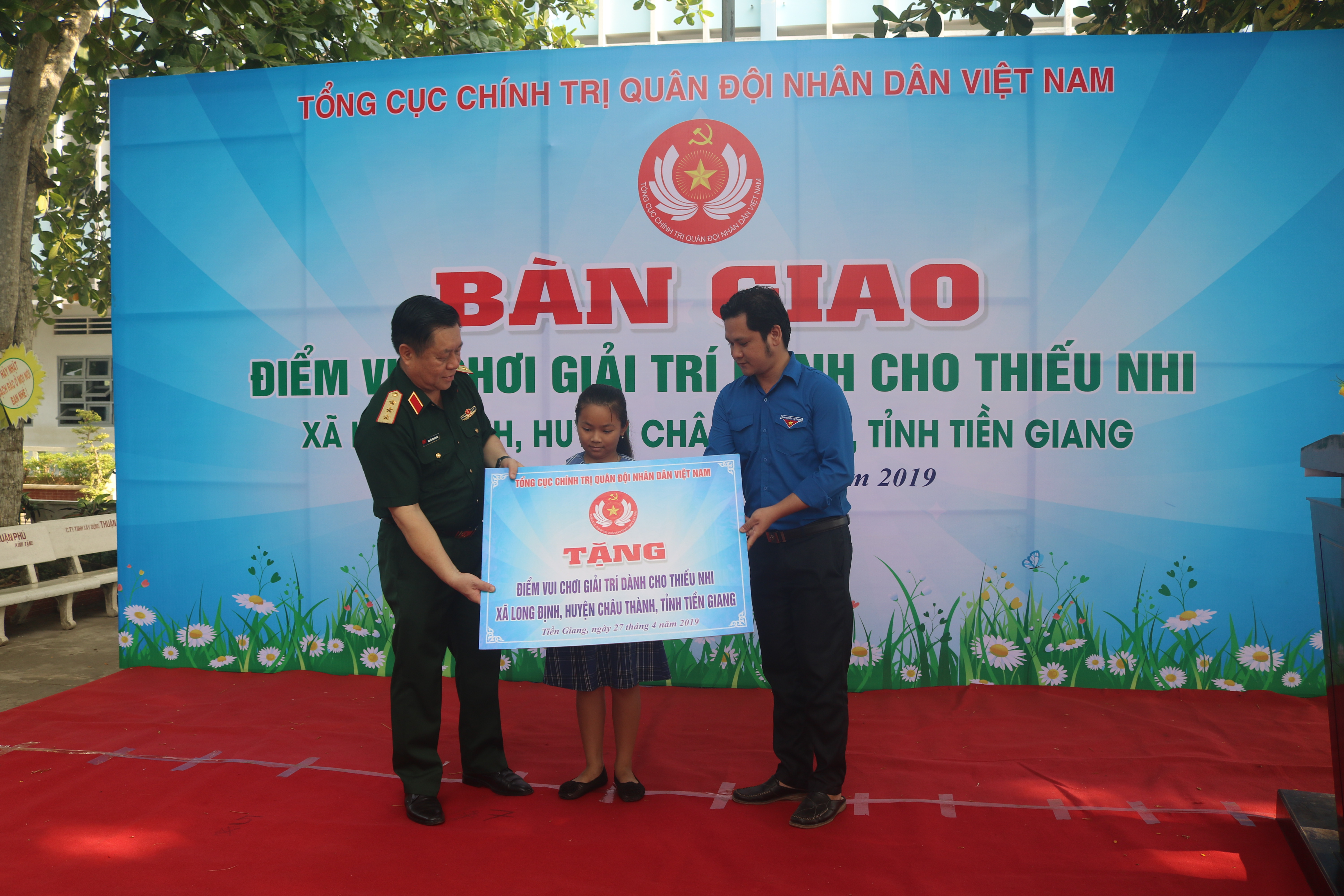 Thượng tướng Nguyễn Trọng Nghĩa và anh Nguyễn Anh Tuấn trao bảng tượng trưng Điểm vui chơi thiếu nhi cho học sinh Trường Tiểu học Giồng Dứa.