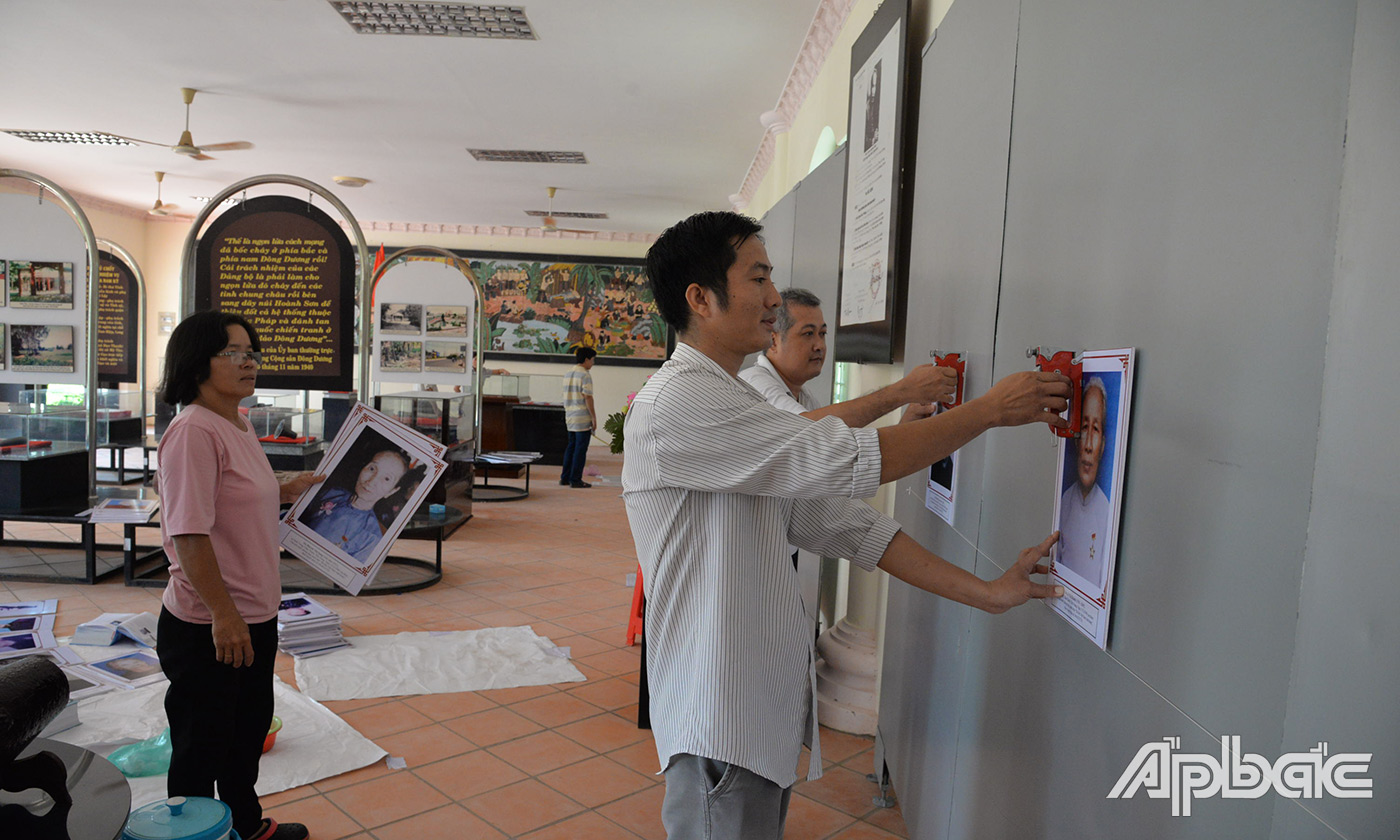 Cán bộ Bảo tàng Tiền Giang đang tiến hành trưng bày hiện vật và hình ảnh bổ sung nhà trưng vày tại di tích lịch sử cấp Quốc gua Đình Long Hưng
