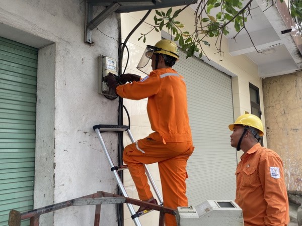 Kiểm tra côngtơ điện cho khách hàng. (Ảnh: Đức Thọ/TTXVN)