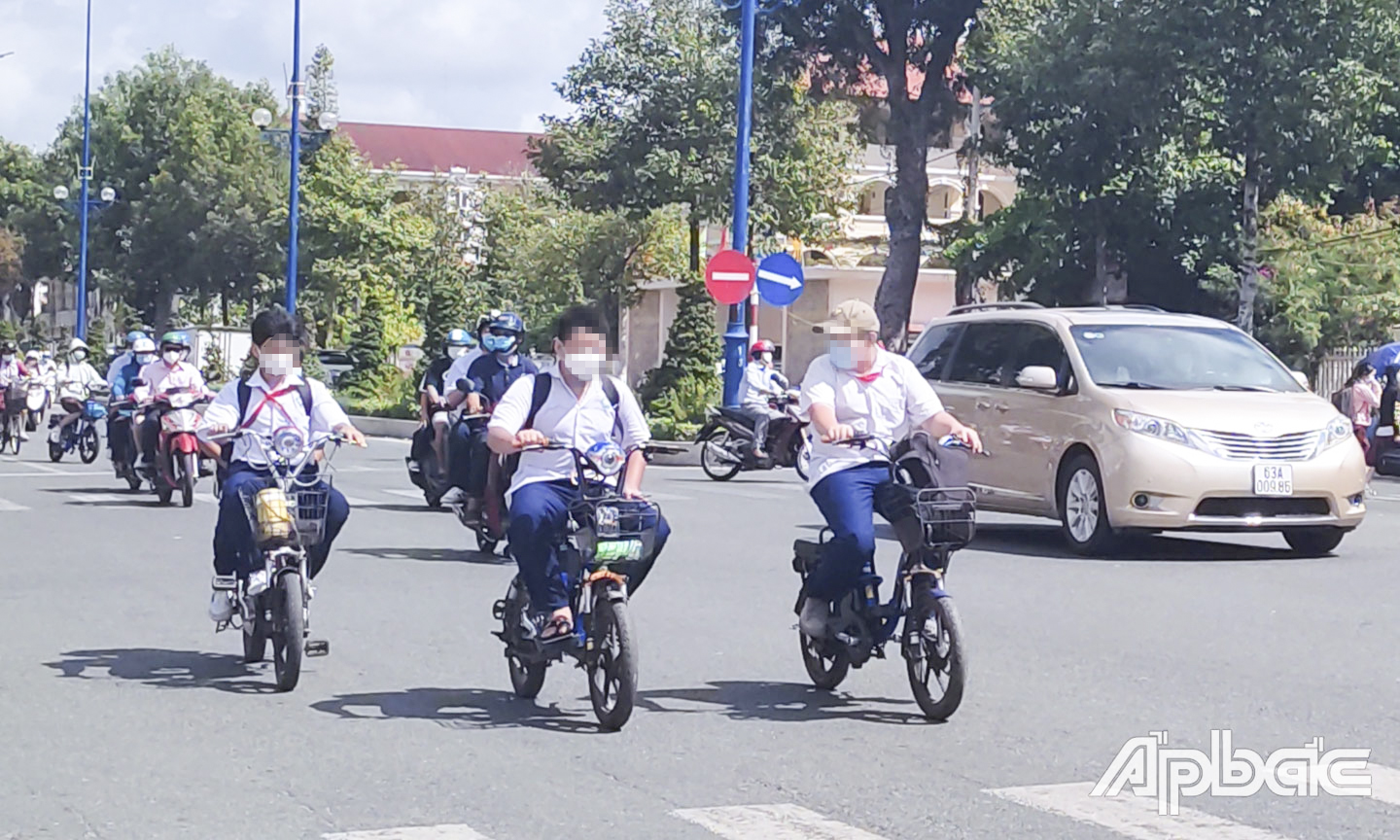 Học sinh không đội nón bảo hiểm khi đi xe đạp điện và đi hàng 3 trên đường Hùng Vương (TP. Mỹ Tho).