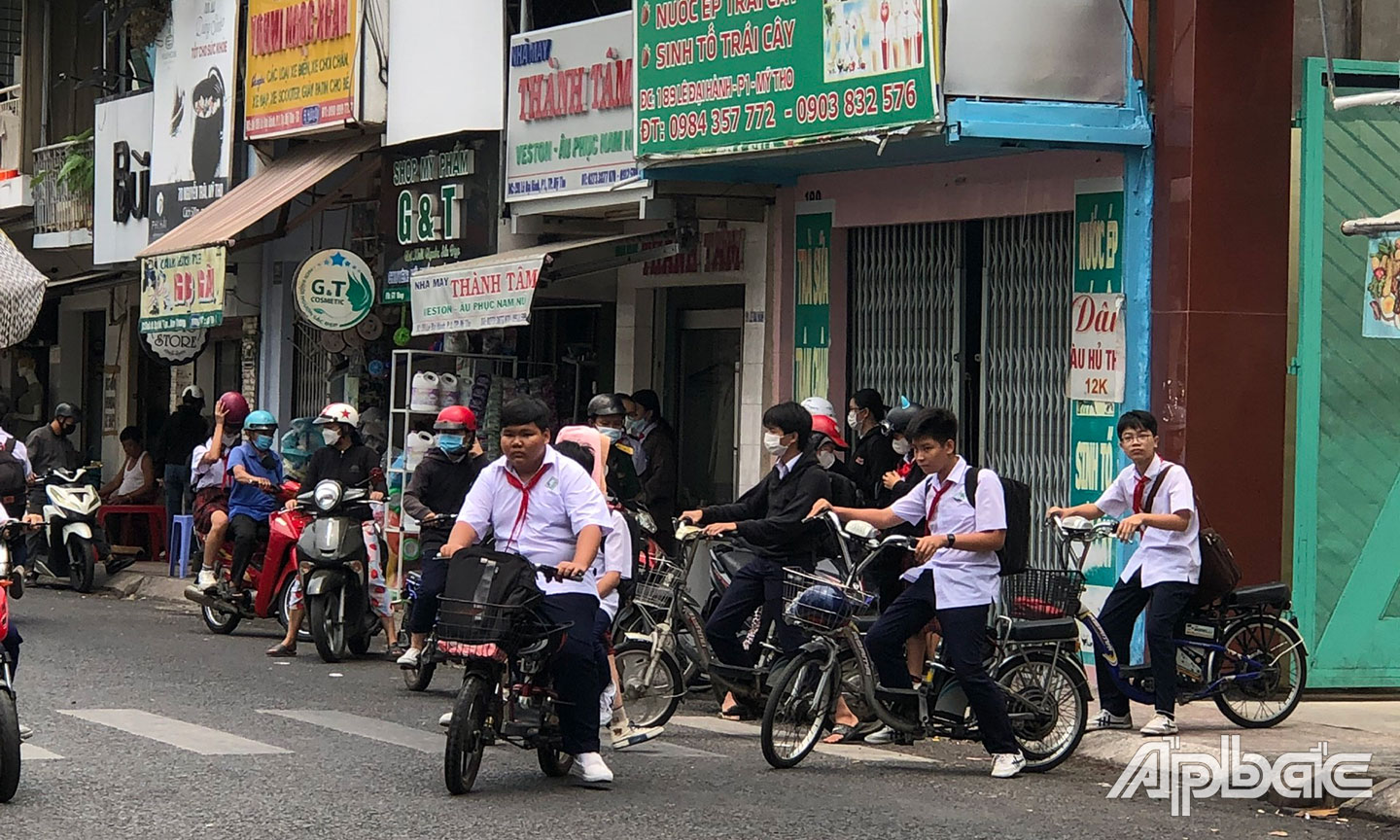 Học sinh đi xe đạp điện không đội nón bảo hiểm tại cổng sau của một trường THCS trên địa bàn TP. Mỹ Tho.