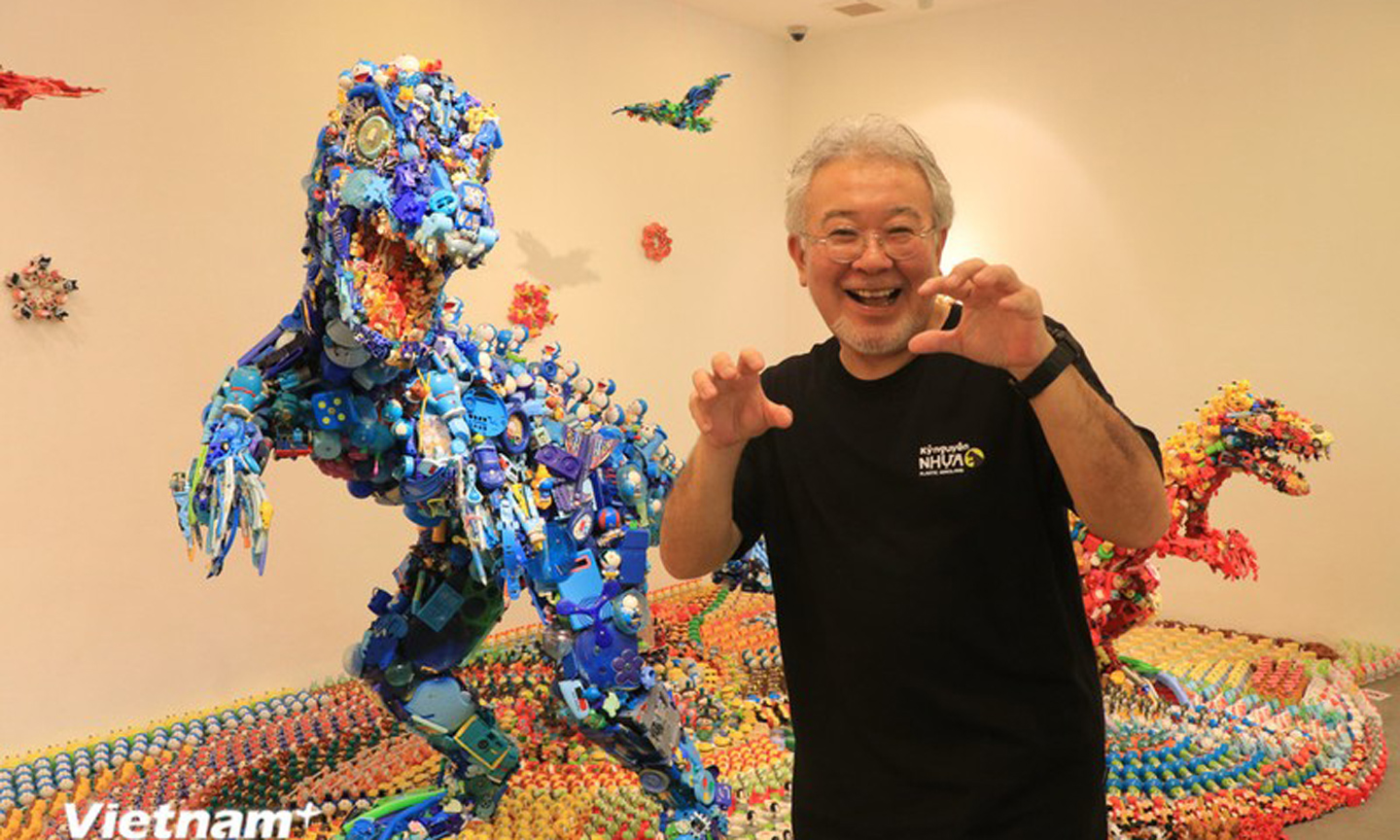 Artist Hiroshi Fuji poses in front of his works at the exhibition (Photo: VN+)