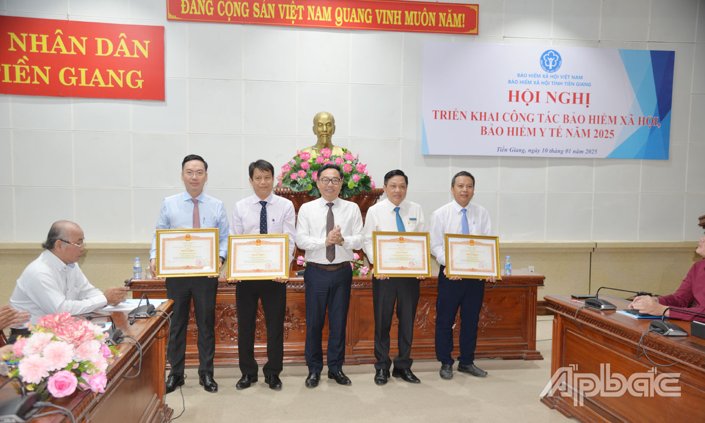 BHXH huyện Cái Bè (bìa trái) nhận Bằng khen của Thủ tướng Chính phủ vì có thành tích xuất sắc trong công tác tại Hội nghị triển khai công tác BHXH, BHYT năm 2025.