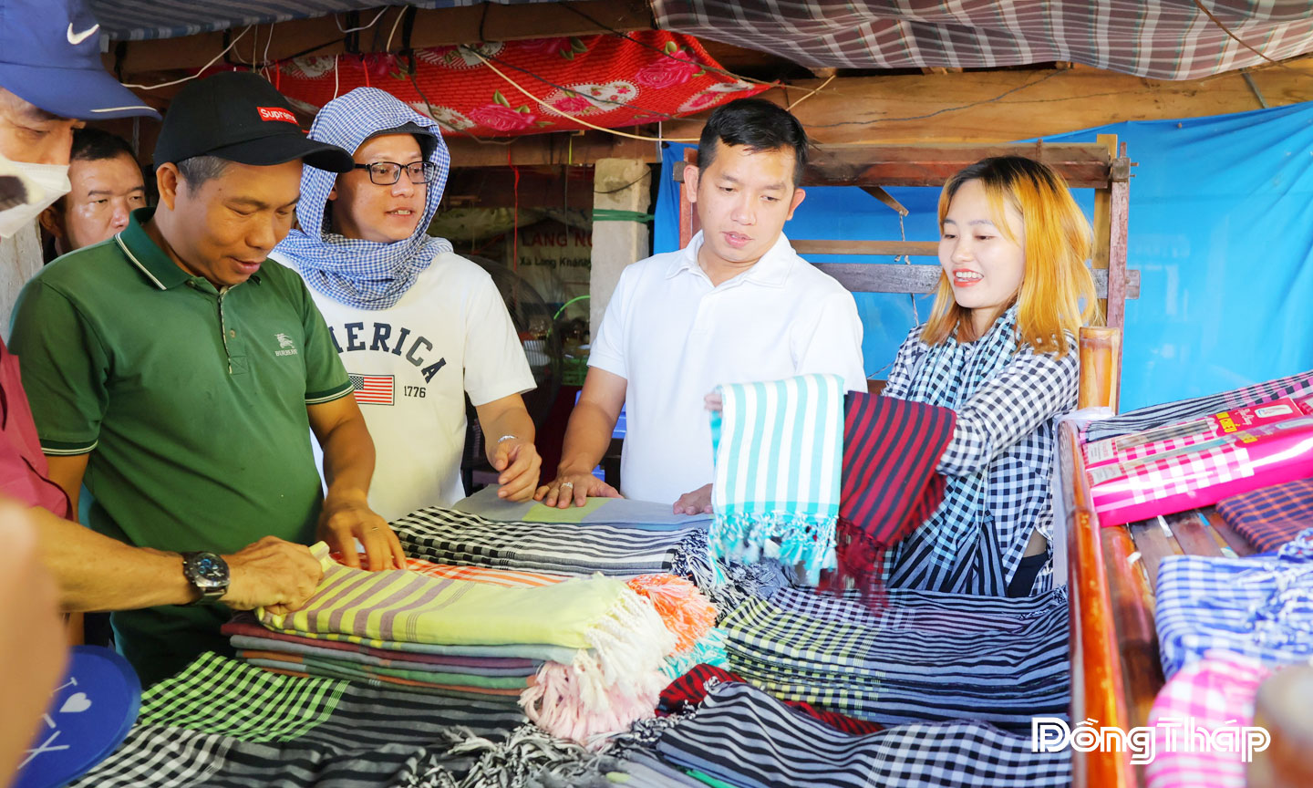 Khách du lịch thích thú khi được người dân Làng nghề dệt choàng Long Khánh A giới thiệu cách để tạo ra một chiếc khăn choàng. 