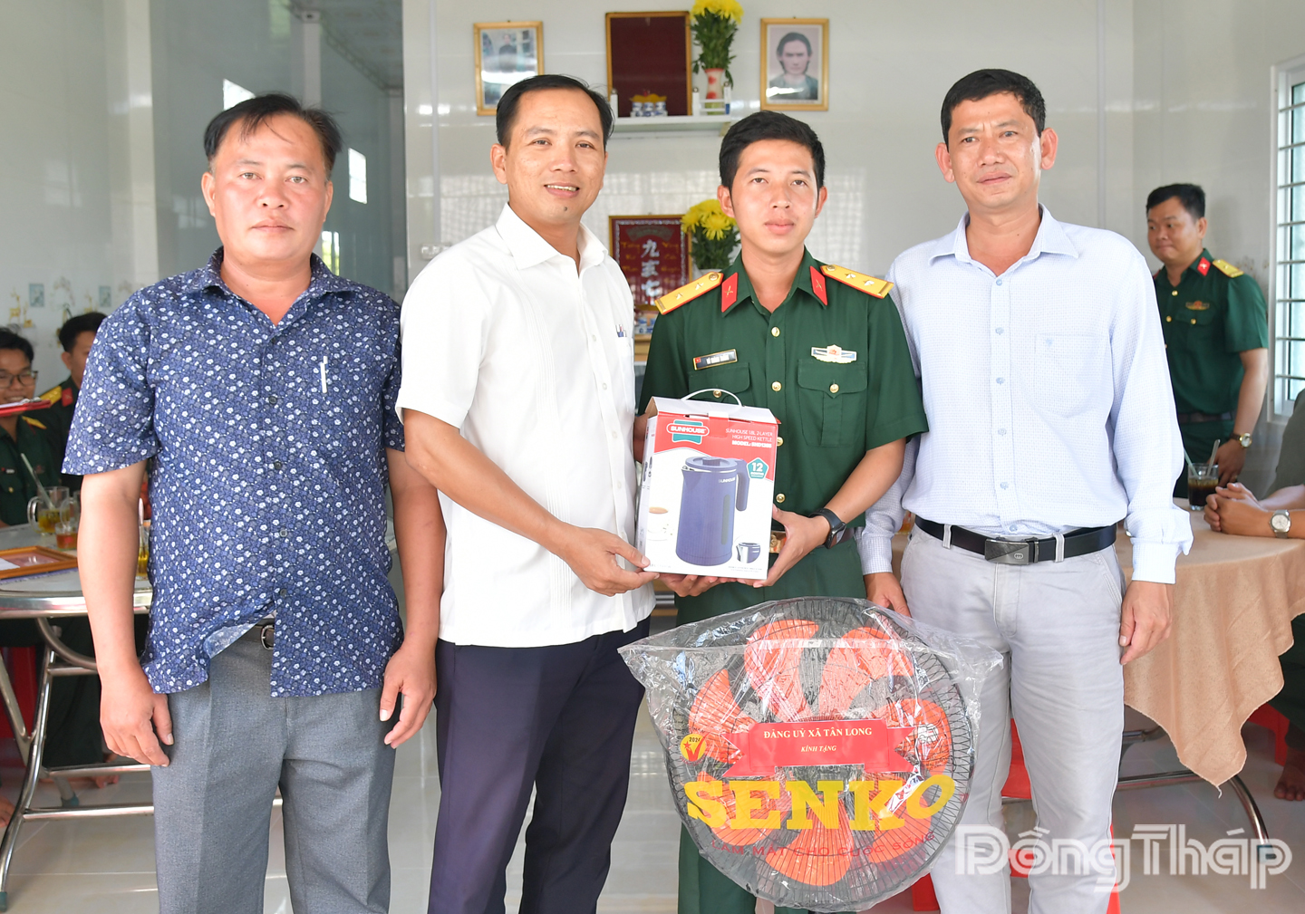 Đồng chí Nguyễn Hoàng Minh Trí, Phó Bí thư Thường trực Đảng ủy xã Tân Long, tỉnh Đồng Tháp (thứ 2 từ bên trái sang) tặng quà chúc mừng Trung úy Võ Thành Thắng được nhận nhà mới.