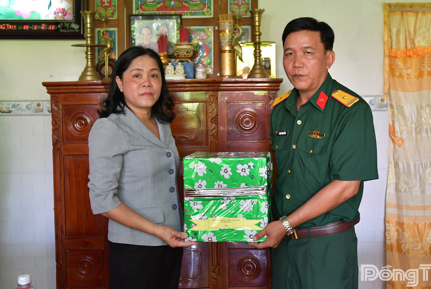 Đồng chí Ca Thị Thúy, Phó Bí thư Thường trực Đảng ủy xã Phú Thọ, tỉnh Đồng Tháp (bìa trái) tặng quà chúc mừng cho Thiếu tá Phạm Ngọc Dũng được nhận nhà mới.