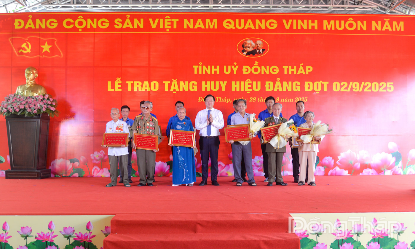 Đồng chí Lê Quốc Phong trao Huy hiệu Đảng và tặng hoa chúc mừng các đảng viên được tặng Huy hiệu 70 và 65 năm tuổi Đảng.