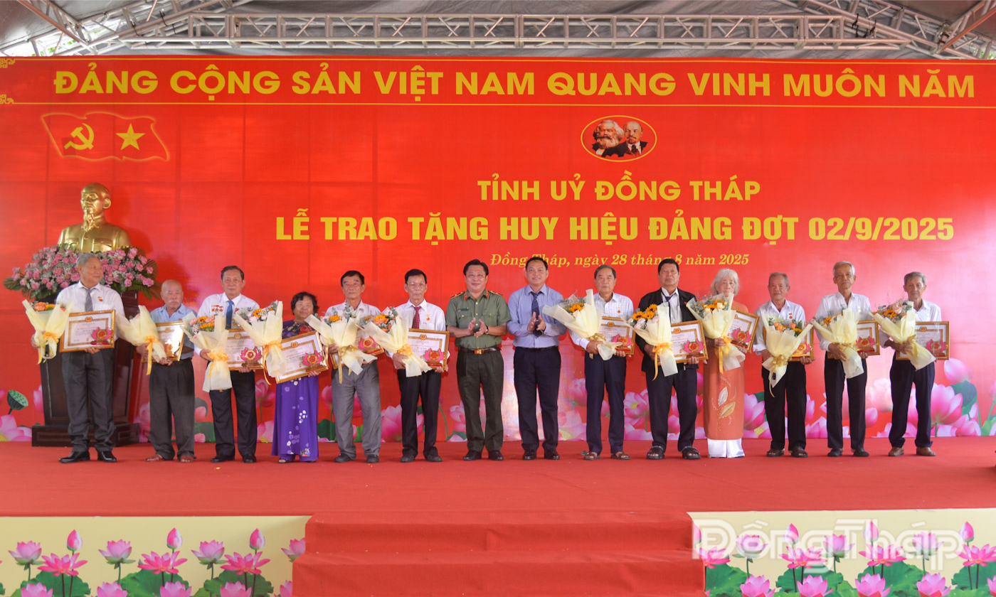 Thiếu tướng Lâm Khắc Nguyên, Ủy viên Ban Thường vụ Tỉnh ủy, Giám đốc Công an tỉnh trao Huy hiệu Đảng cho đảng viên và Đại tá Phạm Văn Thanh, Ủy viên Ban Thường vụ Tỉnh ủy, Chỉ huy trưởng Bộ Chỉ huy Quân sự tỉnh tặng hoa chúc mừng các đồng chí được tặng Huy hiệu 55 năm tuổi Đảng.