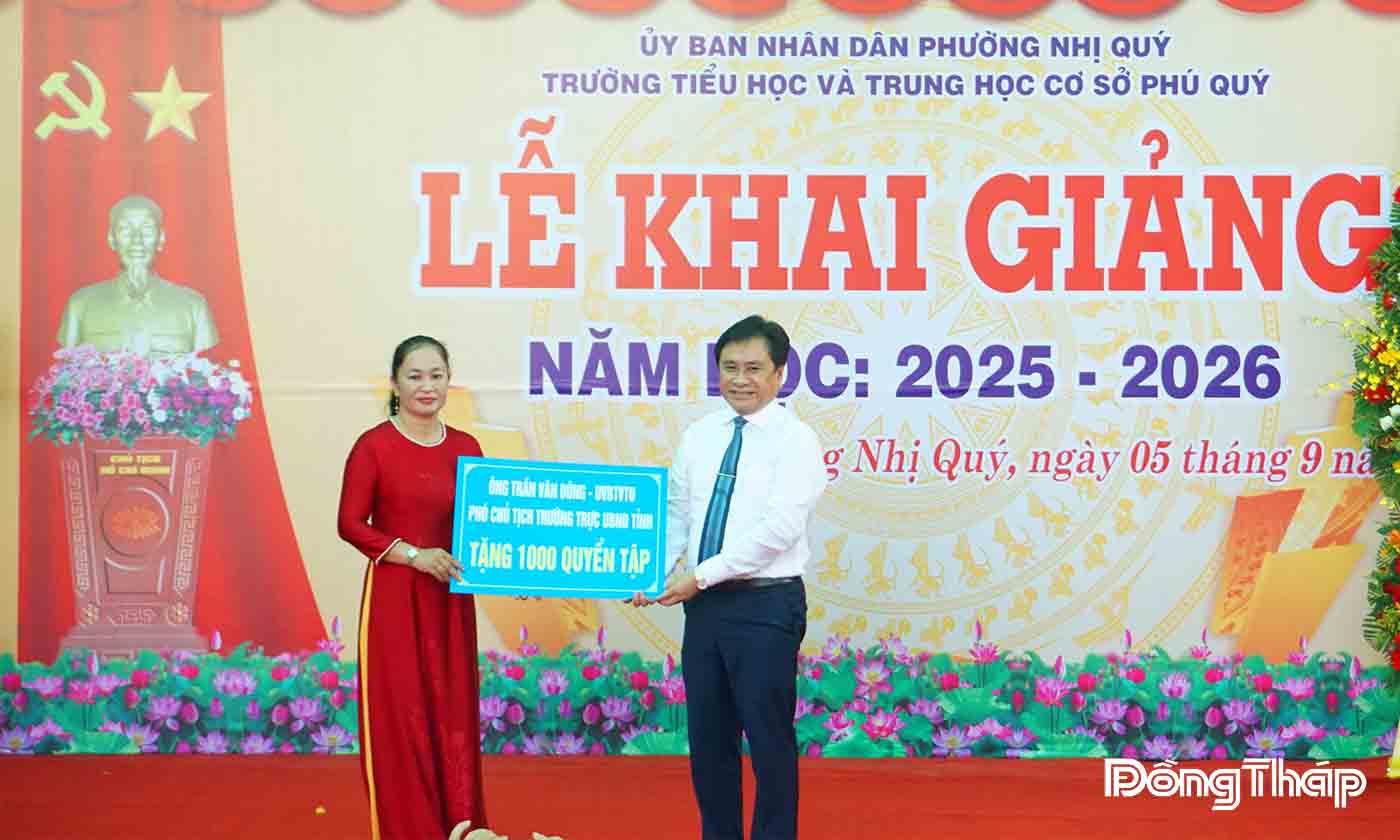 Đồng chí Trần Văn Dũng trao bảng tượng trưng tặng trường 1000 quyển tập cho các em có hoàn cảnh khó khăn