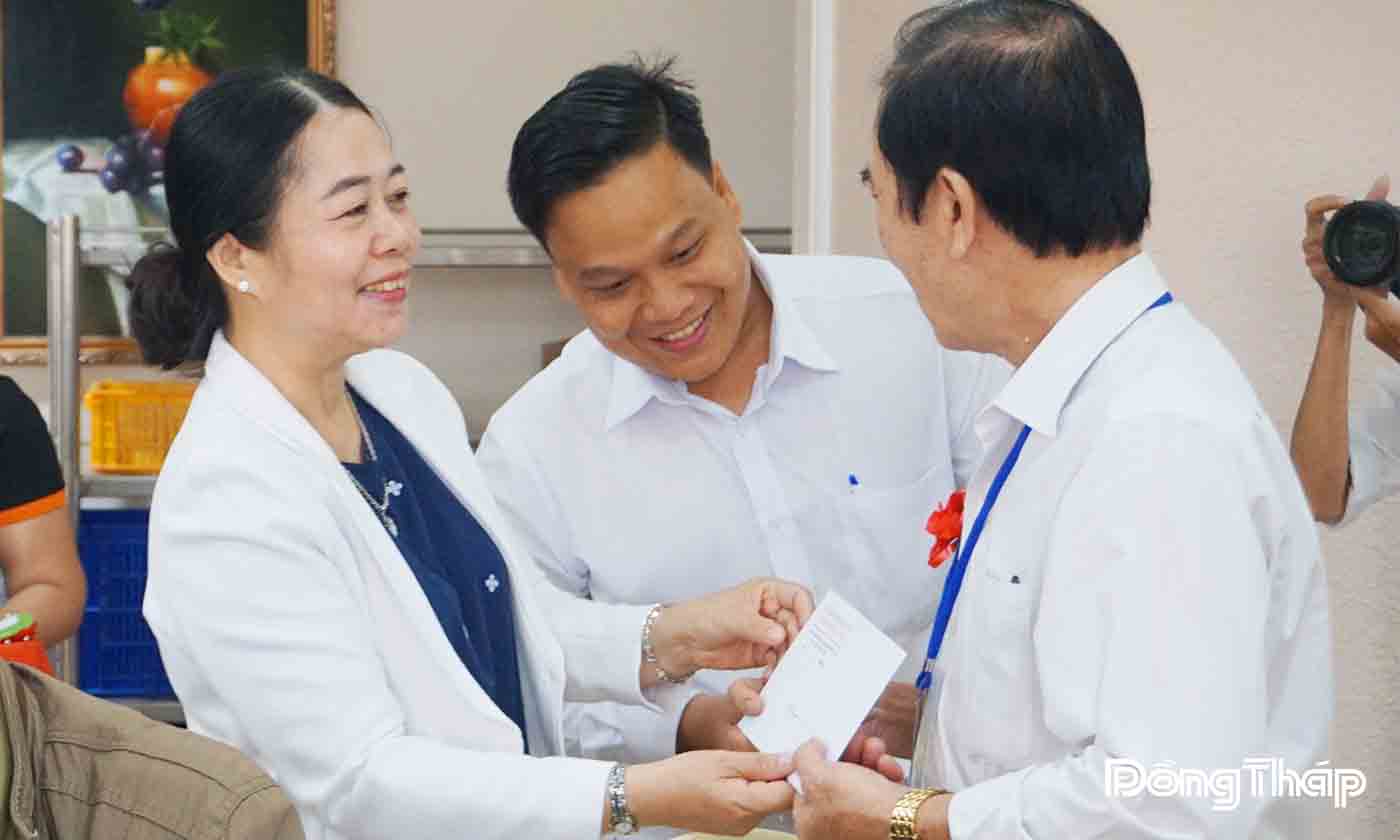 Phó Giám đốc Sở nội vụ tỉnh Đồng Tháp Nguyễn Thị Kiều Loan cài hoa và tặng quà cho người có công trước khi tham quan thủ đô Hà Nội.