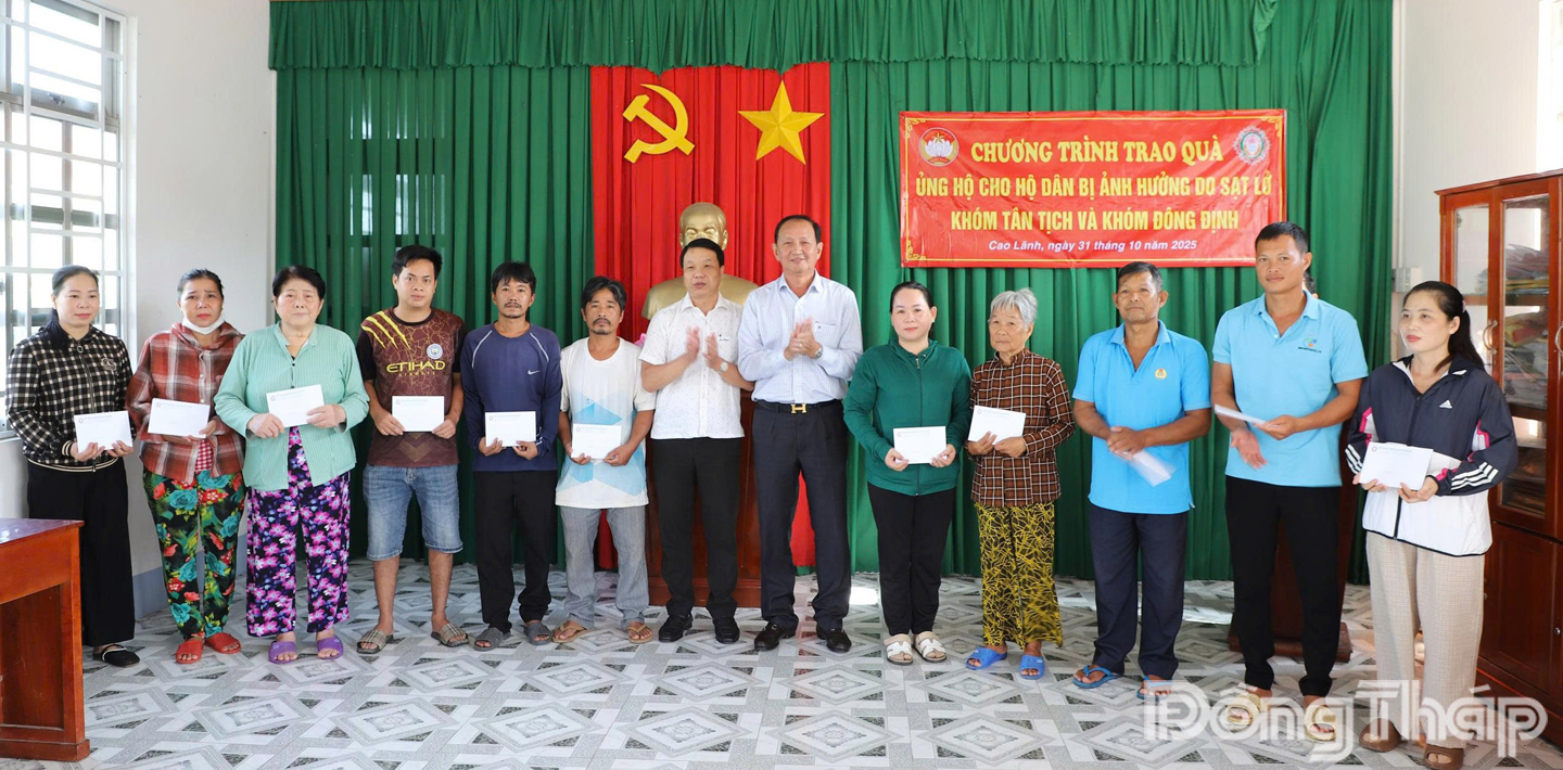 Chủ tịch Công ty TNHH Một thành viên Xổ số kiến thiết Đồng Tháp Lưu Hoàng Tân (thứ 6 từ phải sang) trao tiền cho các hộ dân.