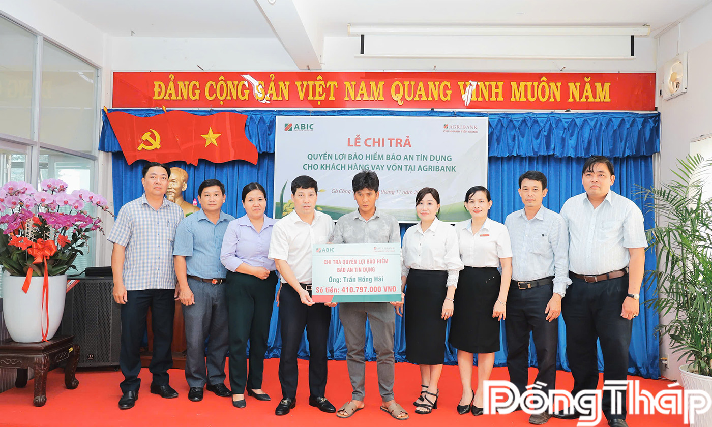 Lãnh đạo ABIC Chi nhánh Bến Tre trao bảng tượng trưng số tiền chi trả quyền lợi bảo an tín dụng cho đại diện các gia đình khách hàng vay vốn.