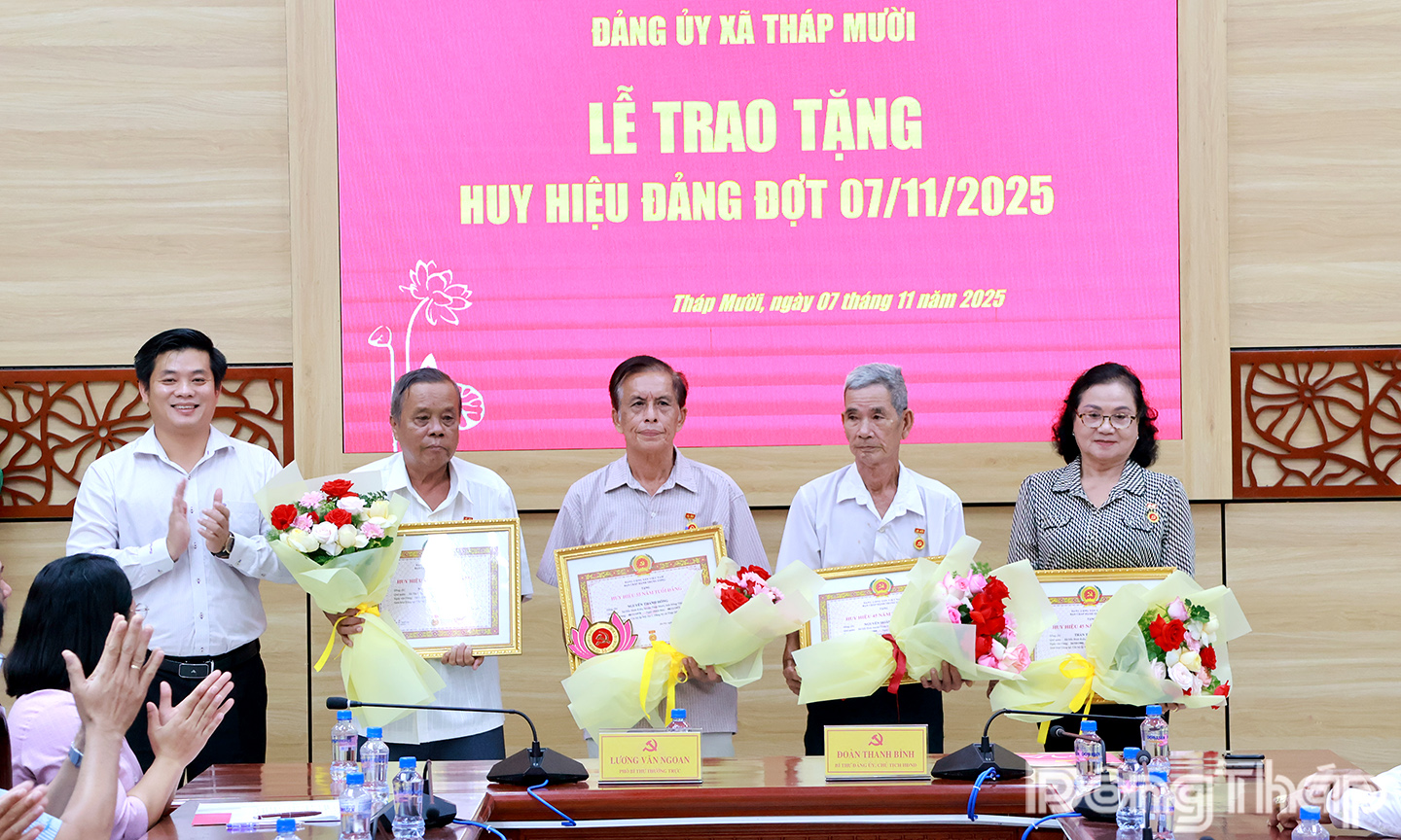 Bí thư Đảng ủy xã Tháp Mười Đoàn Thanh Bình (bìa trái) trao tặng Huy hiệu Đảng cho các đảng viên.