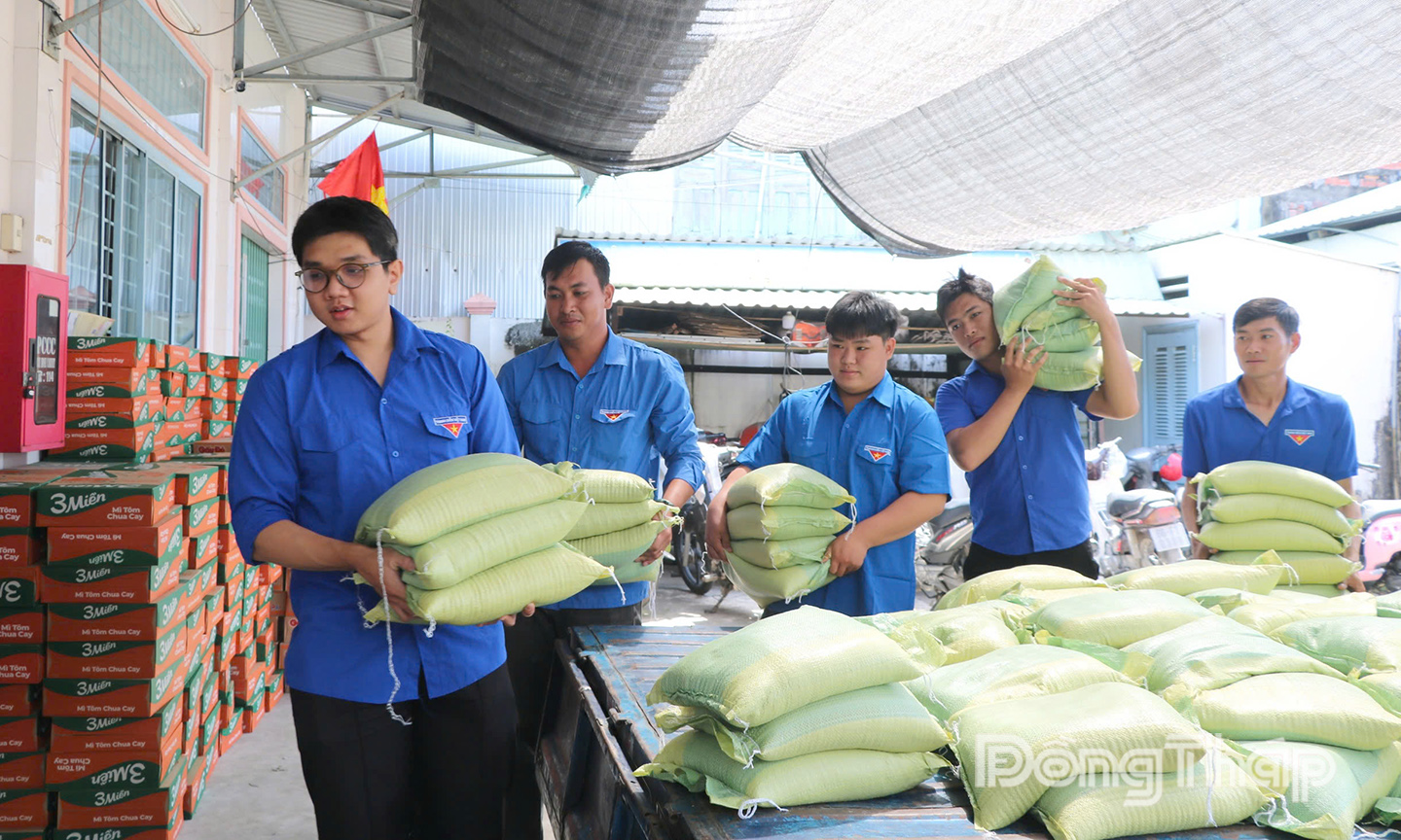 Đoàn viên, thanh niên và thành viên Câu lạc bộ tình nguyện trẻ phường Sa Đéc phụ giúp vận chuyển gạo do mạnh thường quân ủng hộ xuống xe.